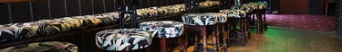 A row of low stools next to three tables and wall mounted bench seating