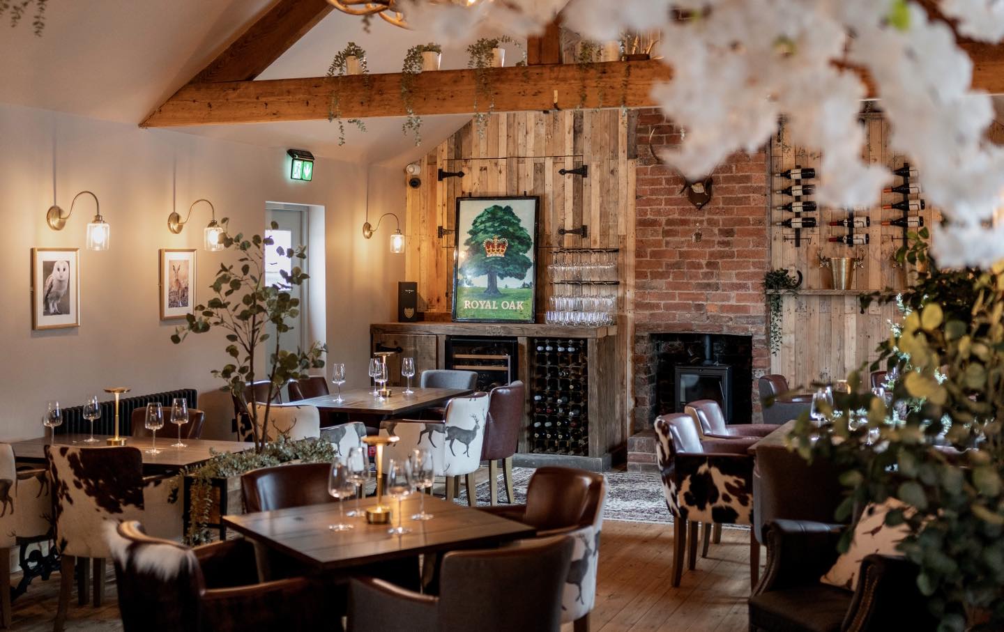 Cozy restaurant interior with wooden beams, a fireplace, and tables set for dining.