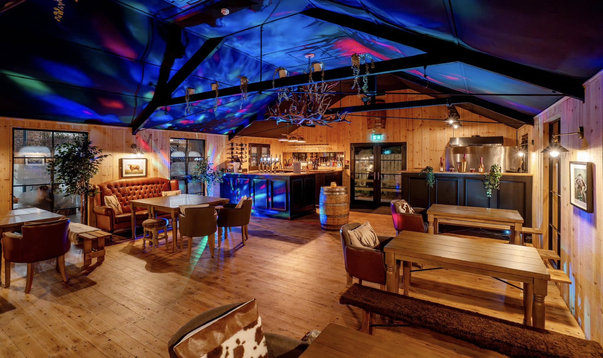 Interior of a cozy restaurant with wooden furniture and colorful ceiling lights.