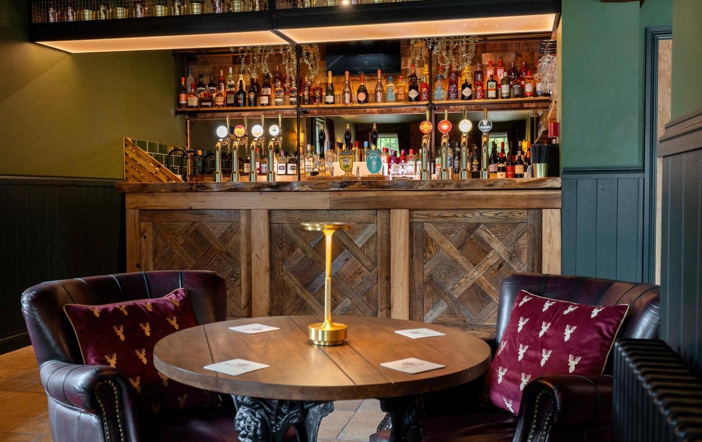 Bar area with wooden table and chairs, featuring a well-stocked bar in the background.