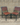 Two wooden chairs with metal frames against a concrete wall.