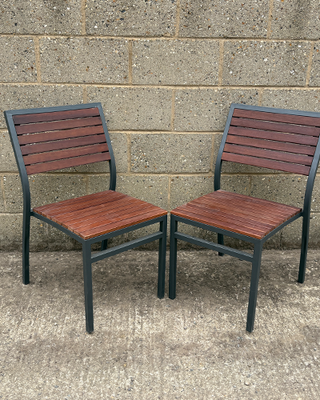 Two wooden chairs with metal frames against a concrete wall.