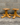 Two wooden stools with a star-shaped base against a concrete wall.