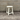 White stool against a gray brick wall on a concrete floor
