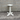 White pedestal table against a gray brick wall.