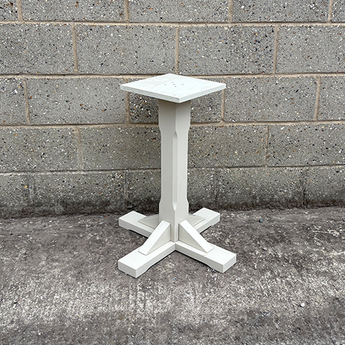 White pedestal table against a gray brick wall.