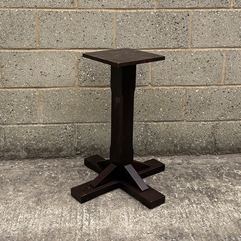 Dark metal table base against a gray brick wall