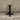 Dark metal table base against a gray brick wall.