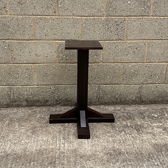 Dark metal table base against a gray brick wall.