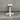 White pedestal table against a gray brick wall.