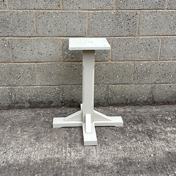 White pedestal table against a gray brick wall.