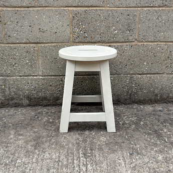White stool against a gray concrete wall