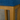 Close-up of a wooden stool with a blue cushioned seat against a concrete wall.