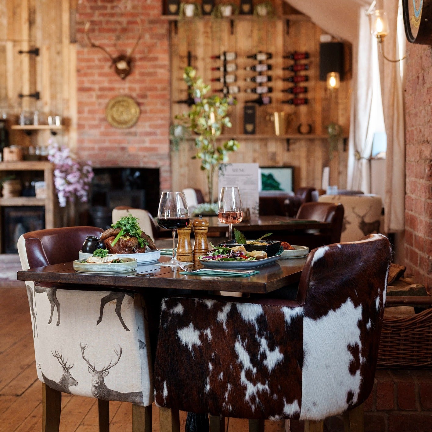 Dining area with rustic decor, including a wooden table and cowhide chairs.