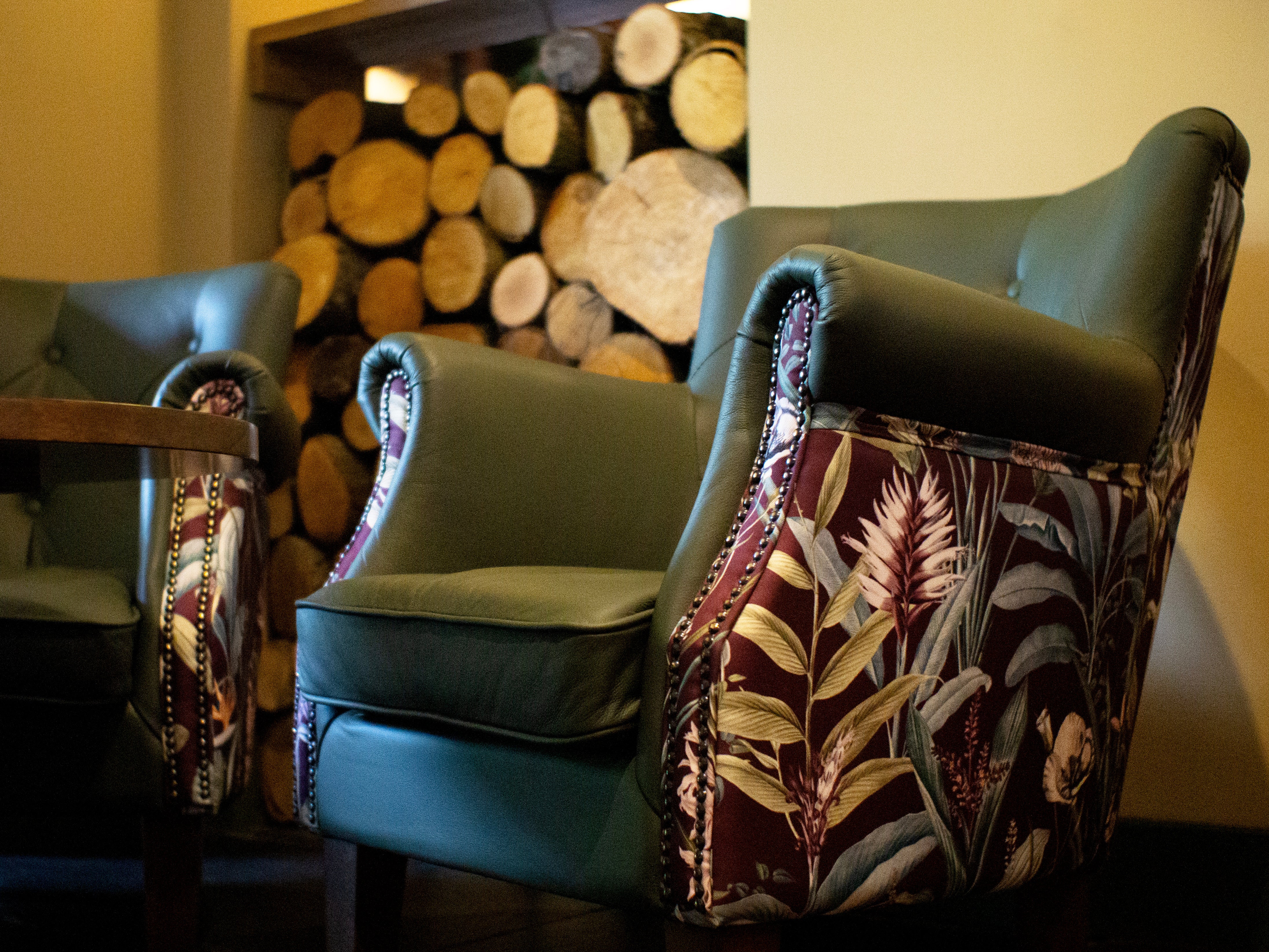 Up close of a sage green Hurricane arm chair with a floral red/purple outter