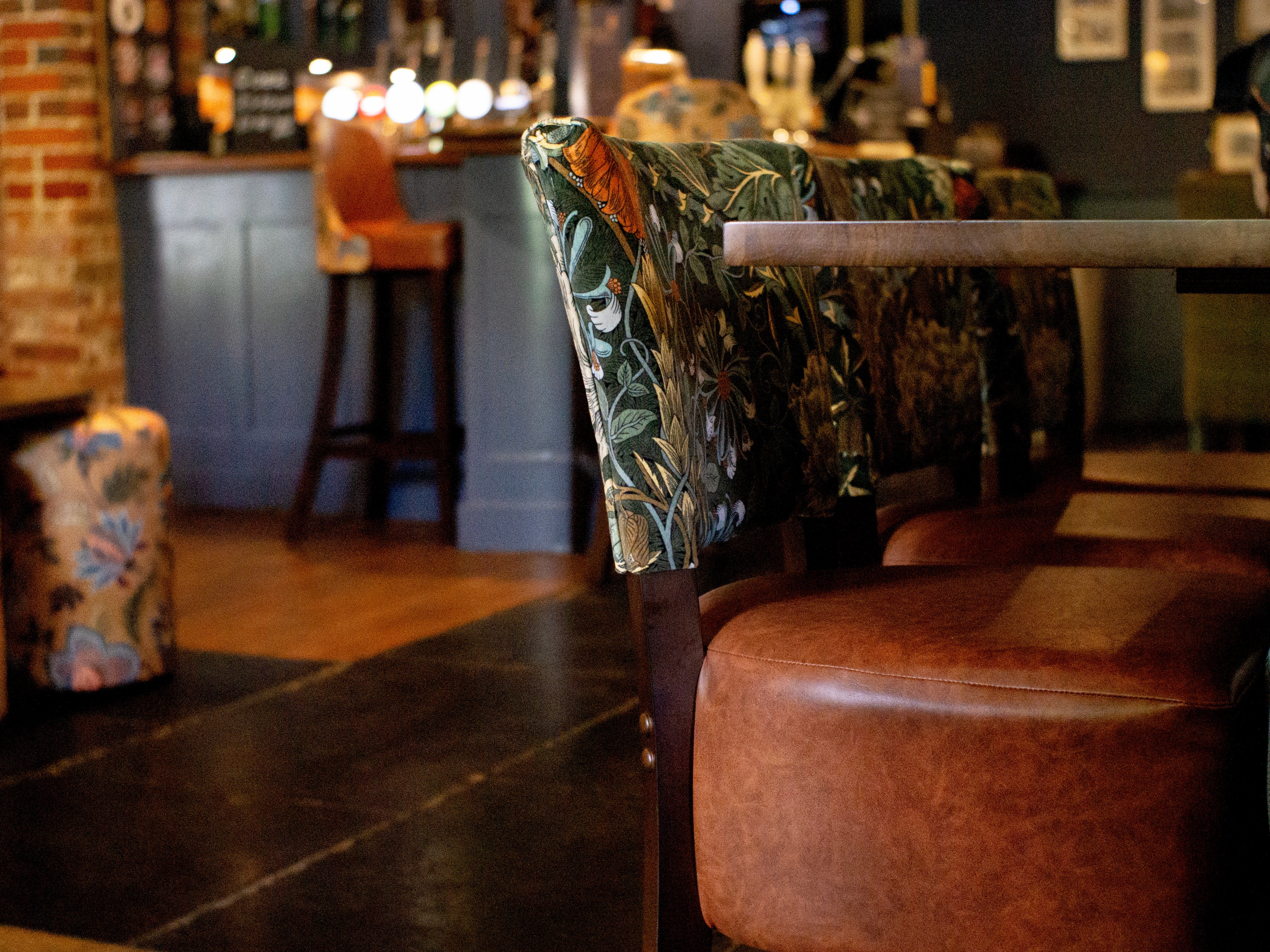 A Luigi dining chair in a pub with green William Morris fabric and brown vinyl seat
