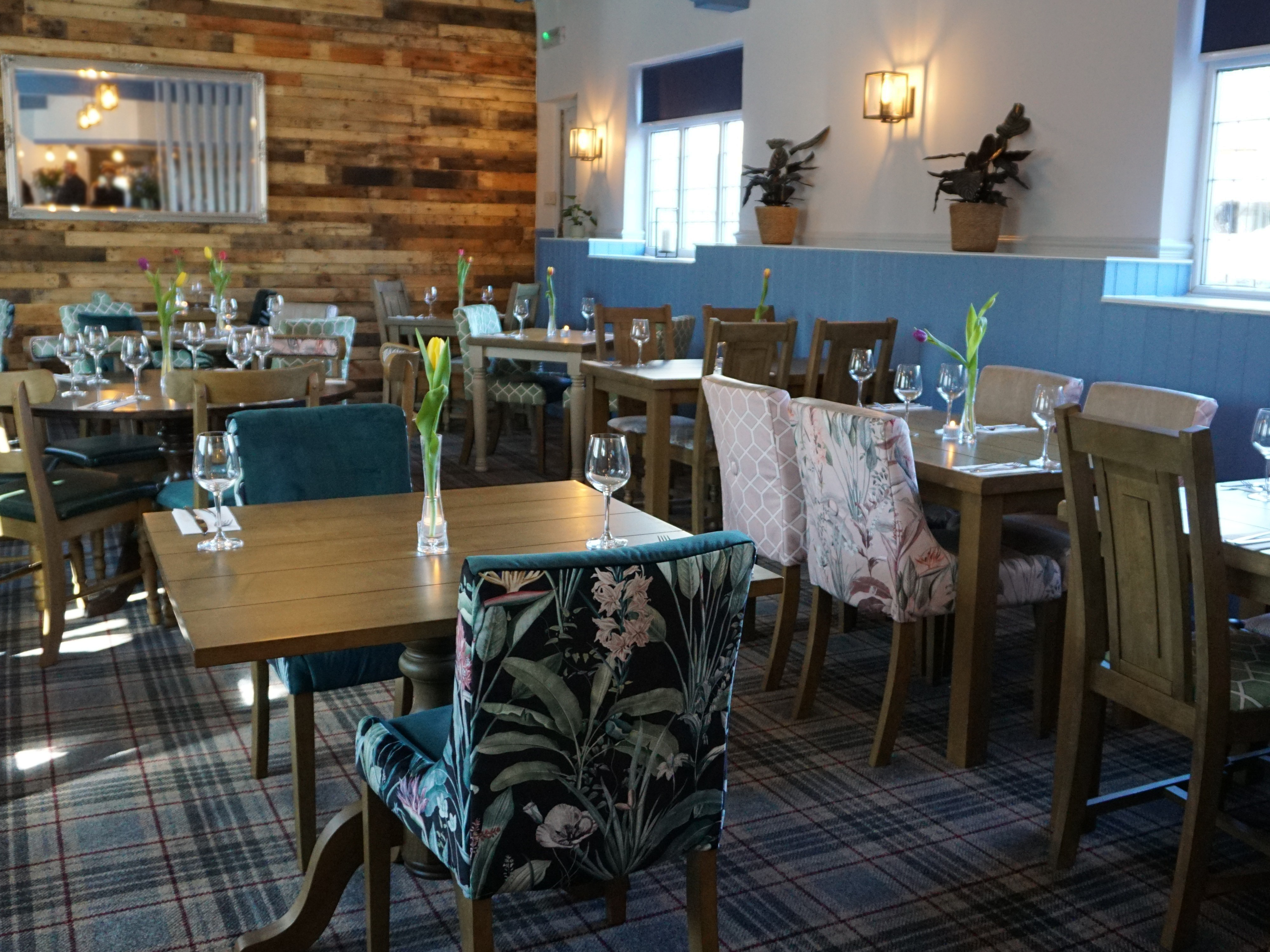 Wide angle shot of a restaurant with pink and blue upholstered chairs